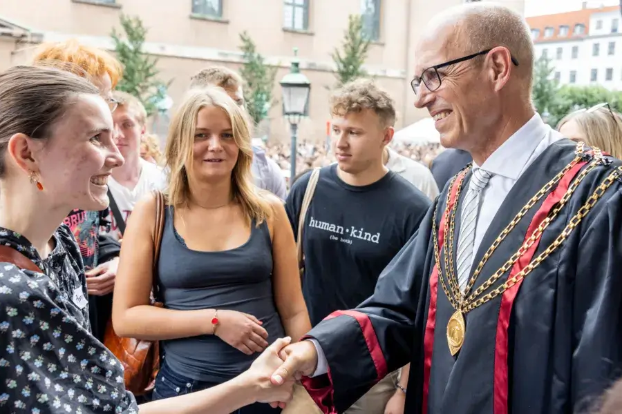 Rektor der giver hånd til de nye studerende til immatrikulationen