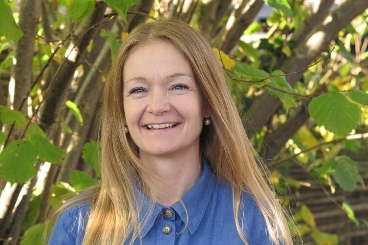 Picture of Dorthe Thomsen, university chaplain at UCPH, smiling outside in front of green plants