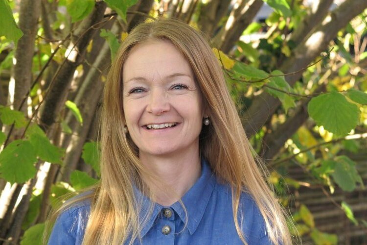 Picture of Dorthe Thomsen, university chaplain at UCPH, smiling outside in front of green plants