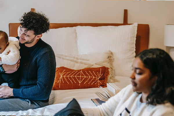 An international couple is sitting with their baby on a bed