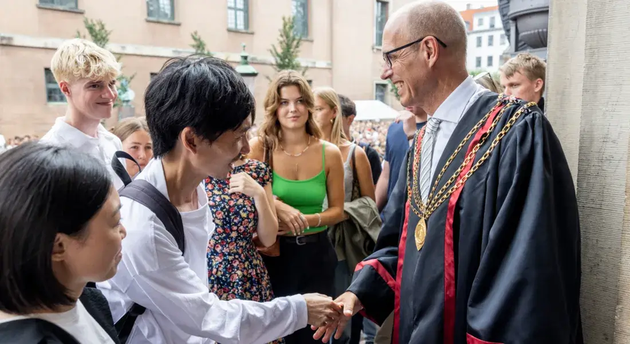 Rektor der giver hånd til de nye studerende til immatrikulationen