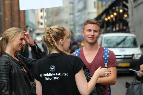 En flok unge studerende står udenfor i t-shirt til studiestart på KU